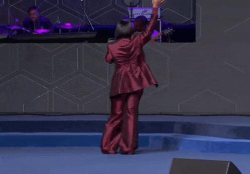 a woman in a red suit stands on a stage