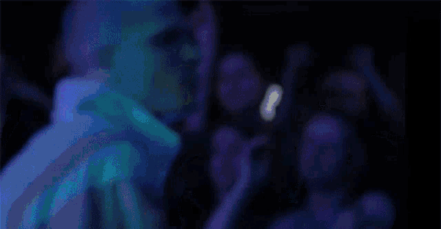 a bald man stands in front of a crowd of people at a concert