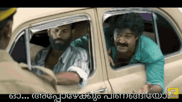 two men are sitting in a car and one of them is wearing a green shirt and has a beard