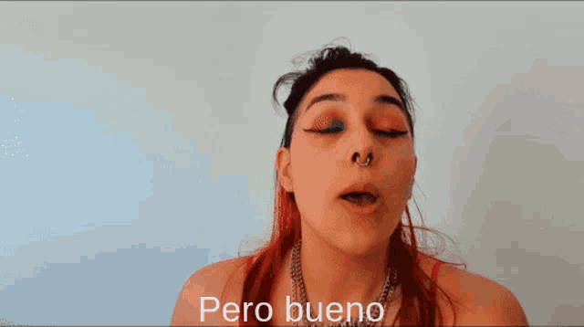 a woman with red hair and a nose ring is making a funny face and the words pero bueno are above her