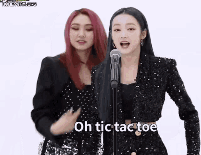 two women are singing into a microphone while dancing .