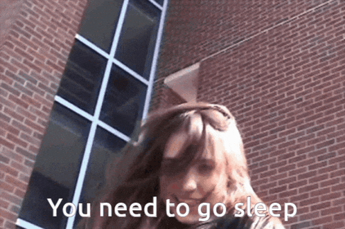 a woman standing in front of a brick building with the words " you need to go sleep " written on the bottom