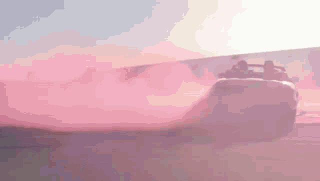 a pink car is driving down a road with smoke coming out of it