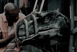 a man is holding the head of a dinosaur in a cage
