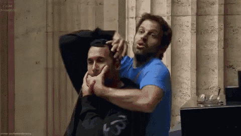 two men are standing next to each other and one of them is holding another man 's neck .
