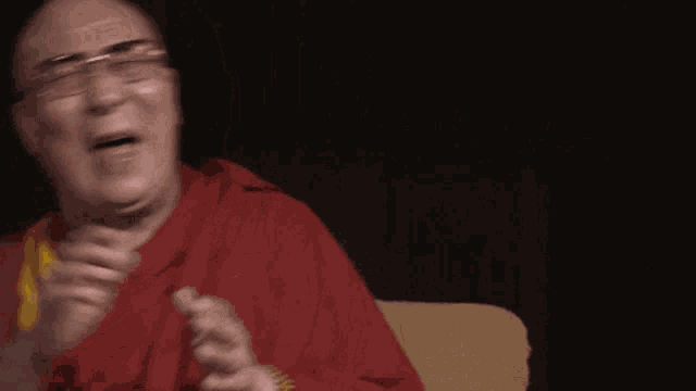 a man with glasses and a red robe is laughing