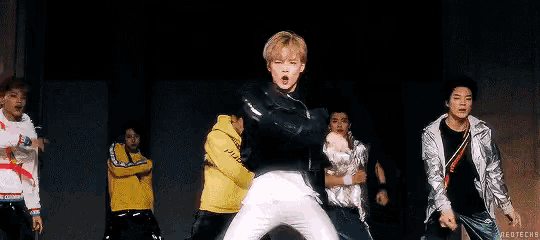a group of young men are dancing on a stage in a room .