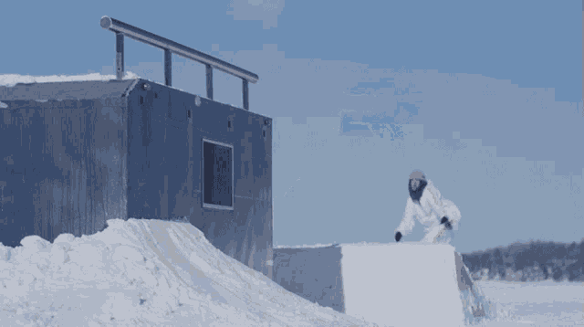 a snowboarder in a white and yellow outfit is going down a snowy ramp