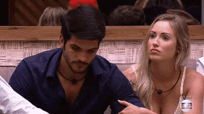 a man and a woman are sitting next to each other and looking at something