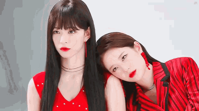 a couple of women are standing next to each other and one of them is wearing a red dress .