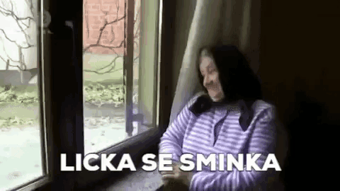 a woman is sitting in front of a window with the words licka se sminka above her .