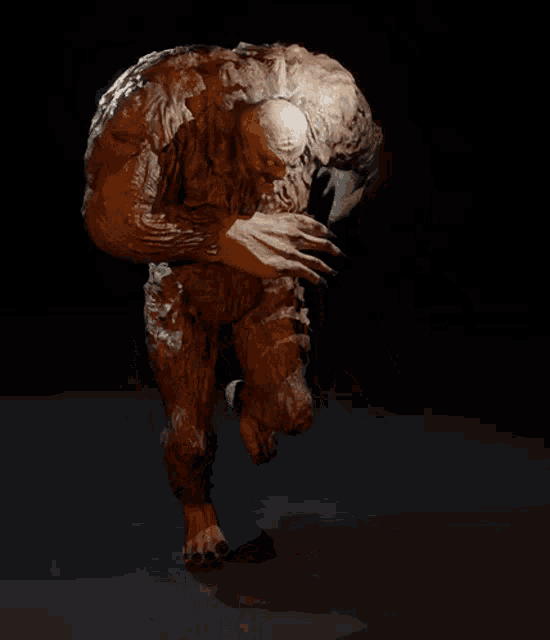 a statue of a monster with huge arms and legs is standing in the dark