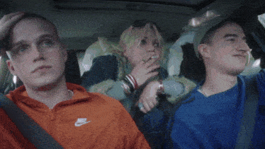 three people in a car one wearing a nike jacket