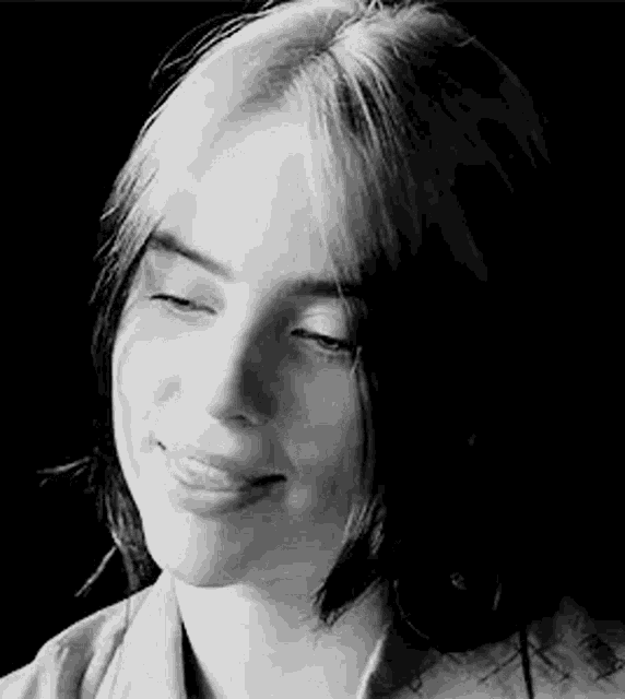 a black and white photo of a woman with her eyes closed and smiling .