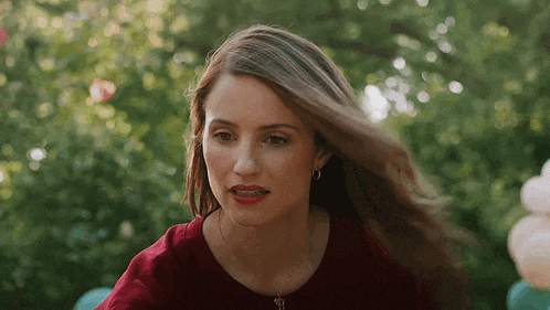 a woman in a red shirt is looking at the camera