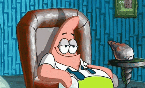 patrick star from spongebob squarepants is sitting in a chair and smiling .