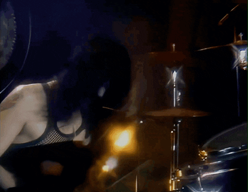 a man in a black tank top is playing drums