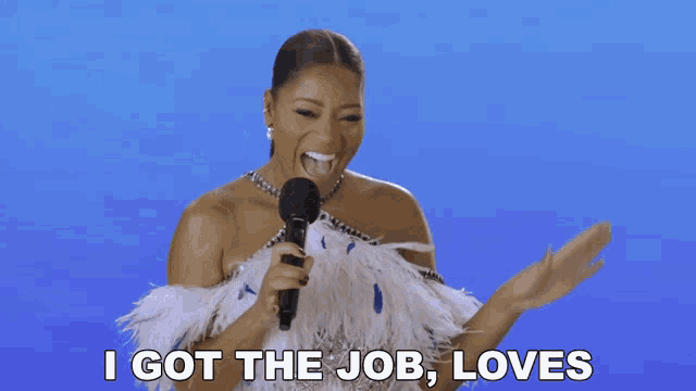 a woman holding a microphone with the words i got the job loves behind her