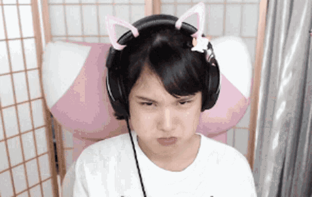 a girl wearing headphones with cat ears on her head looks angry