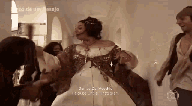 a woman in a white dress is dancing in a hallway with a caption that says denise del vecchio fa clube oficial instagram