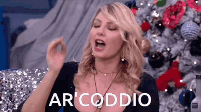 a woman sitting in front of a christmas tree with the word arcoddio written on her face