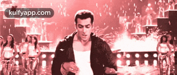 a man in a black jacket is dancing in front of a group of women and the words kulfyapp.com are on the bottom