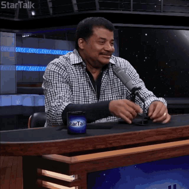 a man sitting at a table with a startalk cup