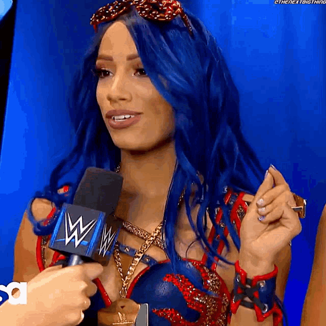 a woman with blue hair is talking into a wrestling microphone