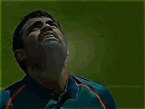 a man in a blue shirt with the letter t on it looks up