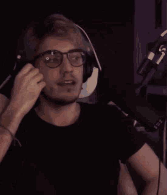 a man wearing headphones and glasses is speaking into a microphone .