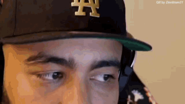 a man wearing a la hat and headphones looks at something