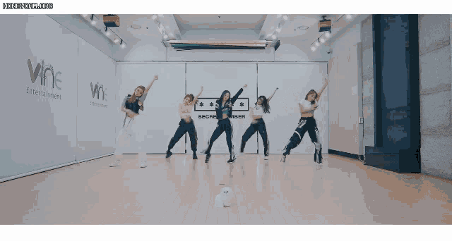 a group of women are dancing in front of a wall that says wne on it