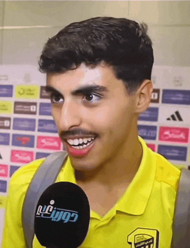 a man wearing a yellow shirt has a microphone in front of him that says ' lg ' on it