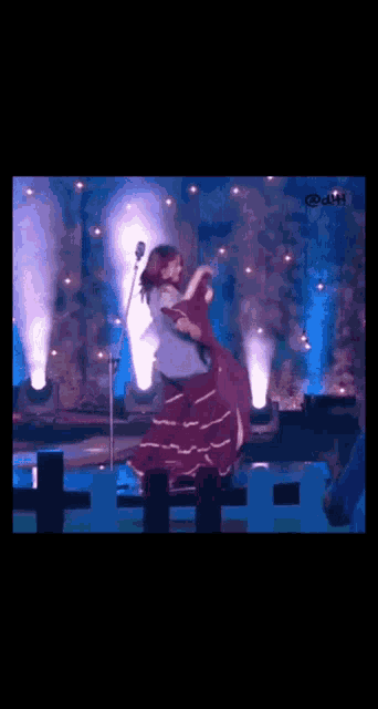 a woman is dancing on a stage in front of a microphone with the number 44 on the bottom left
