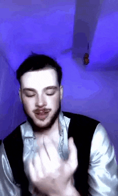 a man with a beard is making a funny face while wearing a vest and a shirt .