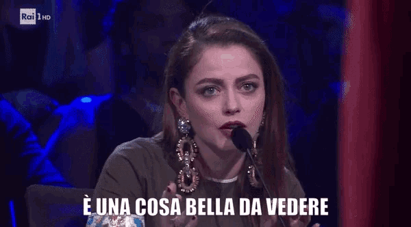 a woman speaking into a microphone with the words e una cosa bella da vedere