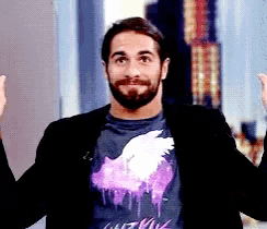 a man with a beard is wearing a black jacket and a purple t-shirt with a swan on it