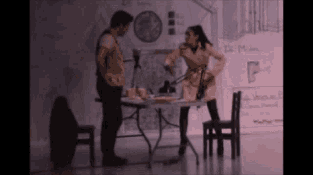 a man and a woman are standing in front of a table with a clock on it