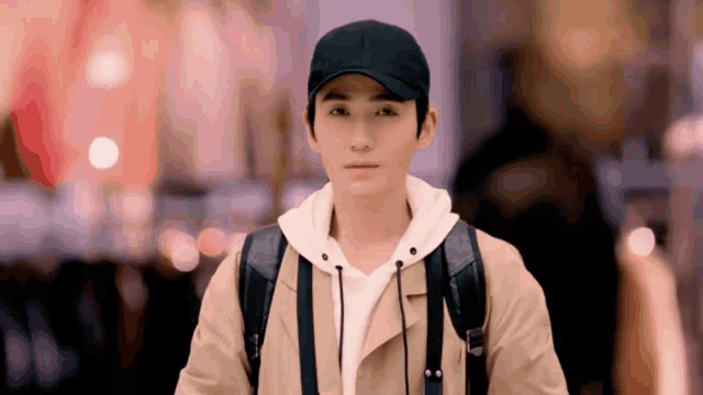 a man wearing a black baseball cap and a tan jacket