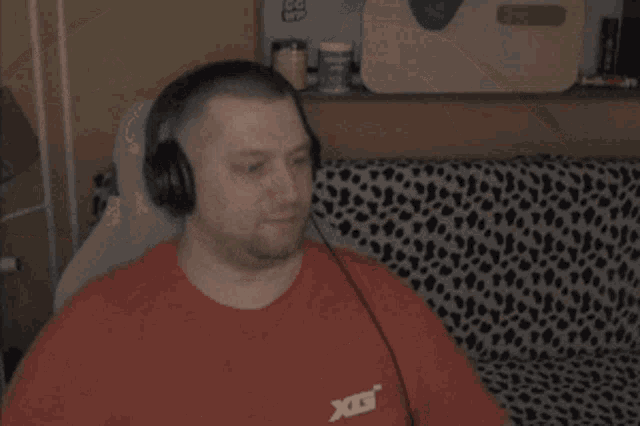 a man wearing headphones and a red shirt is sitting on a couch