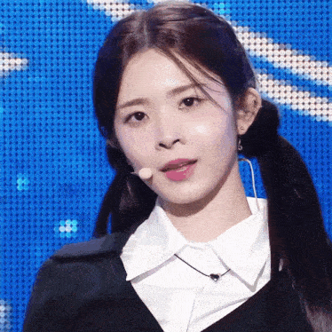 a woman with pigtails is wearing a white shirt and a microphone