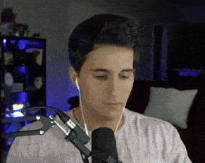 a man wearing ear buds is talking into a microphone .