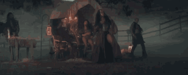 a woman in a long dress is standing in front of a wagon in the fog .