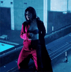 a woman in a bra and red pants is standing on a rooftop