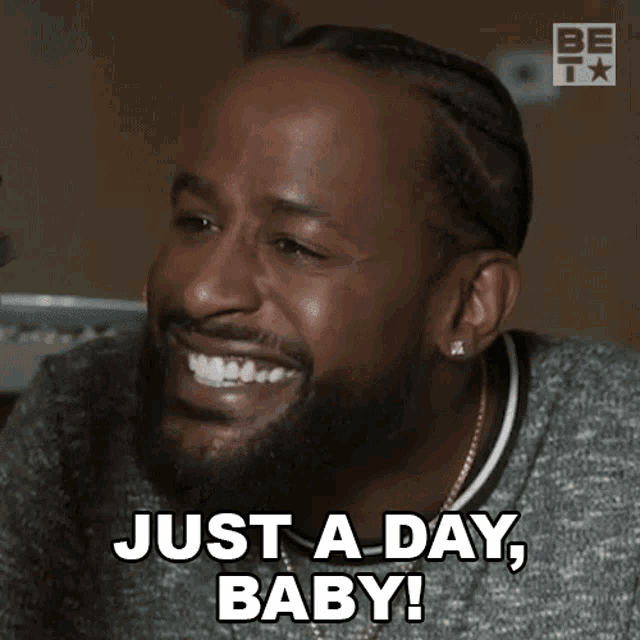 a man with a beard is laughing and says just a day baby