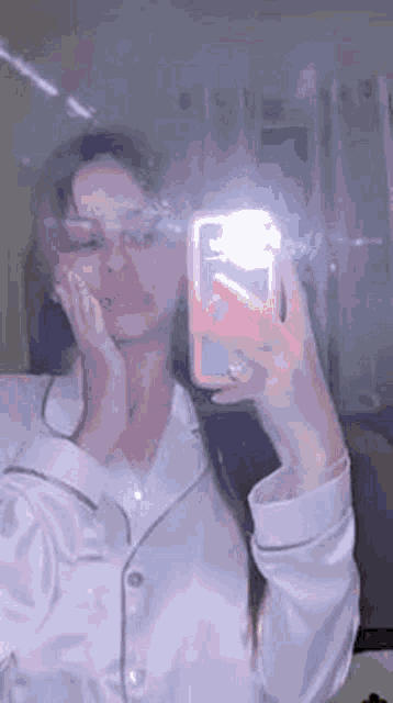 a woman in pajamas is taking a selfie in the mirror .