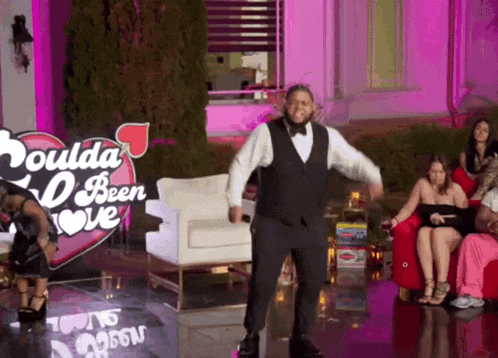 a man in a tuxedo is dancing in front of a sign that says coulda been love
