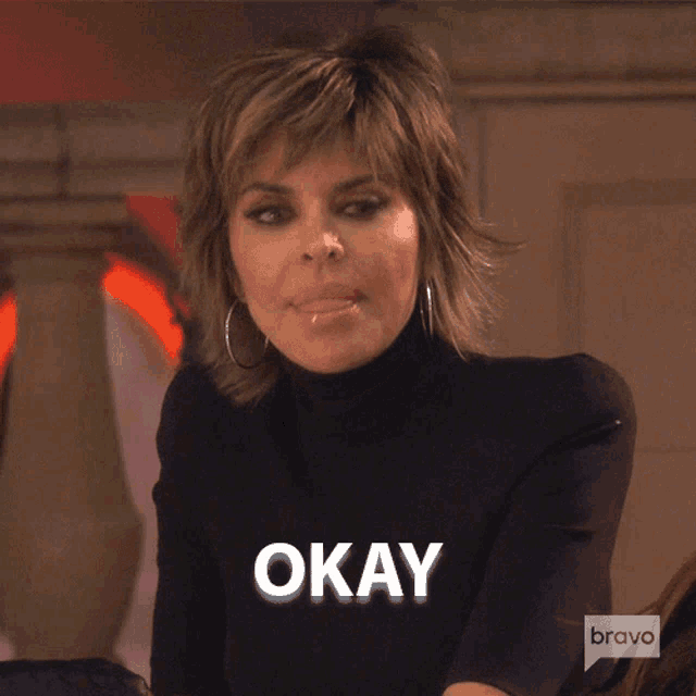 a woman wearing a black turtleneck sweater with the word okay on it