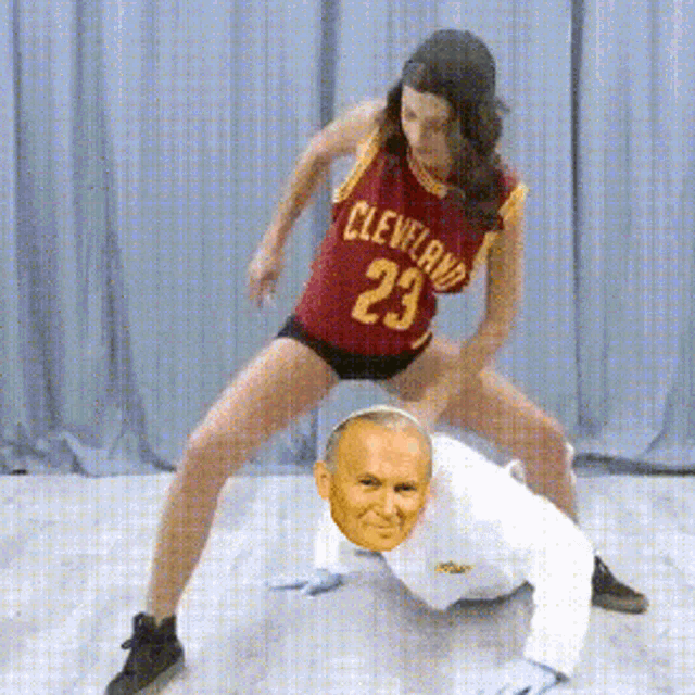 a woman in a cleveland jersey is kneeling on a man 's head