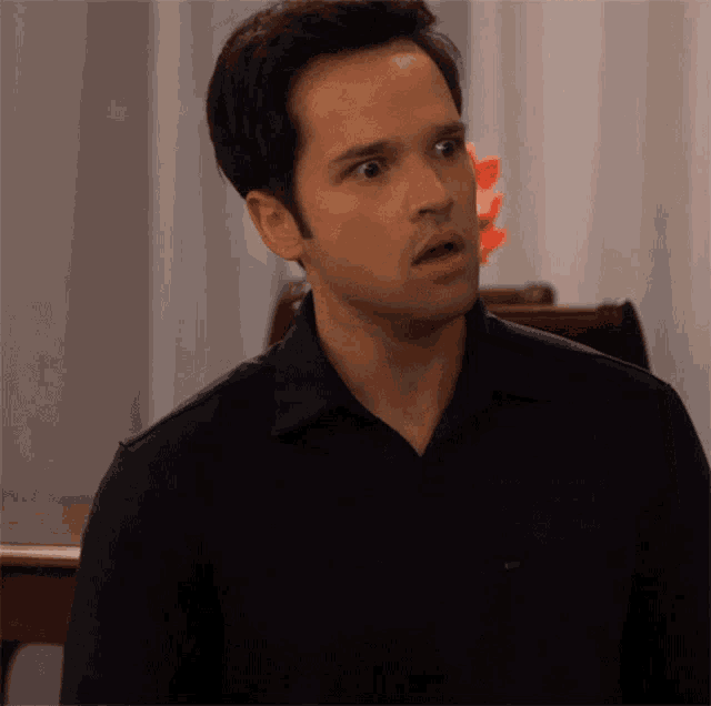 a man wearing a black shirt is making a surprised face